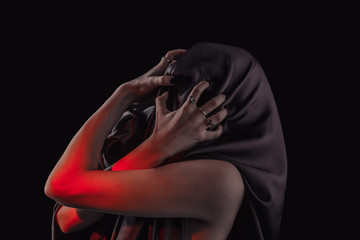 a woman covered with black cloth with a closed face suffers. faceless pain. long black nails on thin female fingers. emotion without facial expressions