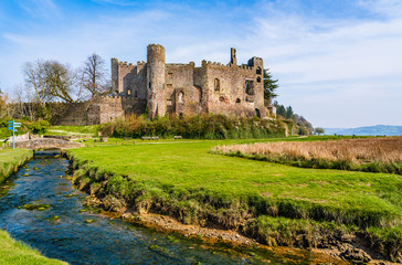 Fototapeta premium Ruins of the medieval Laugharne castle by a stream of water in Laugharne, Pembrokeshire, Wales, UK