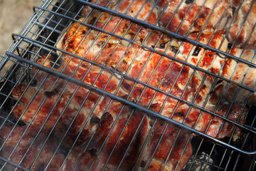 Grilled meat is cooked outdoors on the grill over an open fire or on a portable grill. Selective focus.