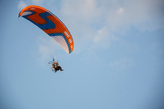 A man is flying a red paraglider.