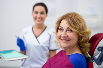 cheerful mature woman and dentist in dental clinic