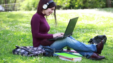 Portrait of cute young woman listening music with headphones in outdoor.