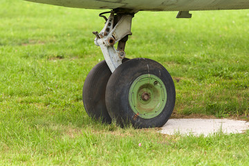 Old landing gear of an old airplane close-up on a background of green grass.