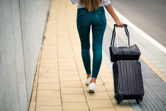 Woman carrying luggage while walking on the street.