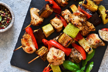 Barbecue of chicken on skewers with vegetables on stone background. Picnic.