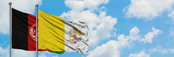 Afghanistan and Vatican City flag waving in the wind against white cloudy blue sky together....