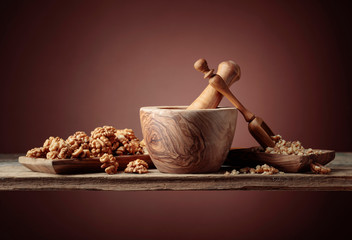 Crushed and whole walnuts in a wooden dish on an old wooden table.