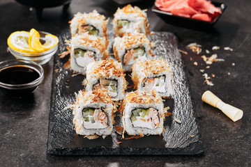 Macro shot of uramaki sushi rolls with cream cheese, fried salmon, tuna shavings or dried bonito, cucumber, nori. Fresh katsuobushi roll in Japanese restaurant closeup