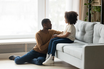 Caring African American father comforting adorable preschool daughter