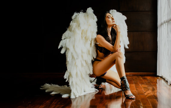 Portrait of beautiful sexy Asian woman with big angel's wings sitting in her room.