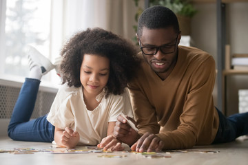 African American father with preschool daughter assembling puzzle