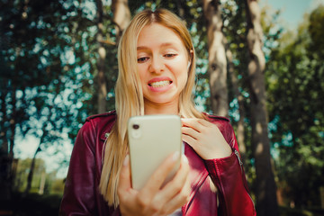 shock shout beautiful young pretty girl looking at the screen display of mobile phone reading...