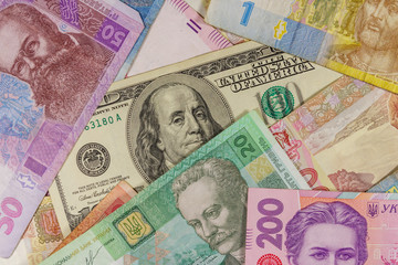 One hundred dollar bill on a background of ukrainian hryvnia banknotes