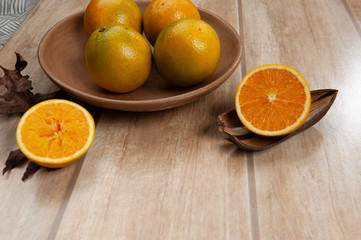 Orange, natural fruit, half used, foreground, slight blur.Second, natural fruit, unfiltered. Light wood color background, top view.
