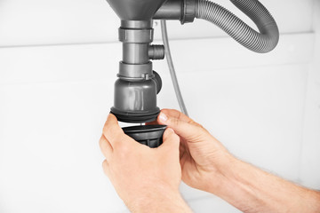 Plumber repairing pipes in kitchen