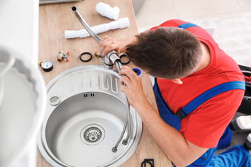 Plumber installing sink in kitchen
