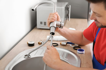 Plumber installing sink in kitchen