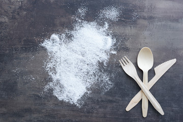 Top view of scattered sugar and fork, spoon, knife from wood. Creative decoration on background of marble kitchen counter.