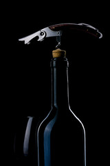 A bottle of wine. Wine glass. Natural cork. Metal corkscrew.