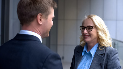 Smiling male and female business partners looking each other, company colleagues