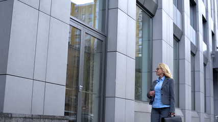 Happy female politician admiring reflection in office building glass, career