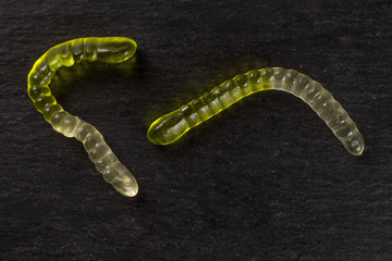 Group of two whole green white colourful jelly worm candy flatlay on grey stone