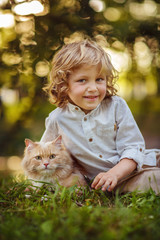 Little curly boy with a redhead cat, outdoor