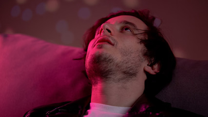 Male drug addict with cocaine at nose feeling high at rave party, nightclub