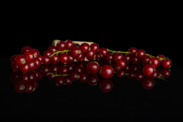Lot of whole fresh red currant with wooden scoop isolated on black glass