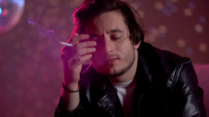 Fototapeta premium Man smoking cigarette on party in club, nicotine addiction, tobacco industry