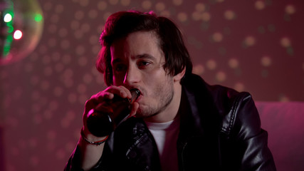 Upset pensive man drinking beer at nightclub disco party, thinking about problem