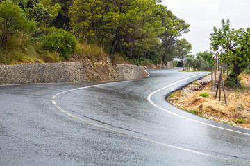 Curved wet asphalt road in a rainy day