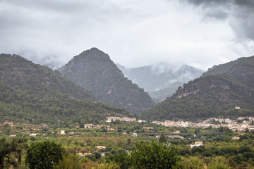 Fototapeta na wymiar View of a small village with mountains in the fog as a background. Mallorca, Spain