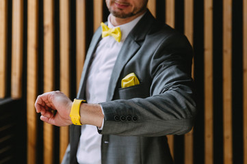 Stylish man in a gray suit looks at the smart watch on his hand