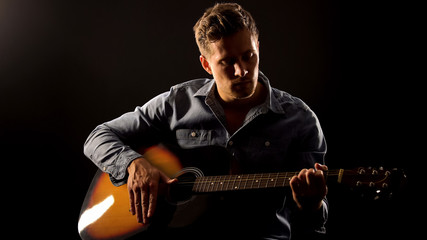 Romantic male playing guitar on date, isolated on black background, hobby