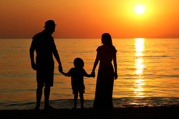 family silhouette at sunset by the sea...
