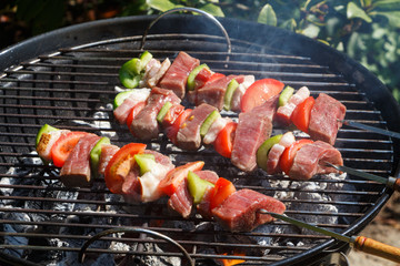 Beef brochette grilling on the rack of a barbecue