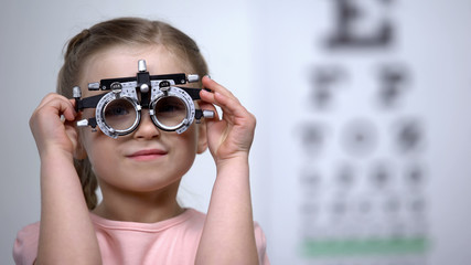 Pretty girl in optical trial frame smiling seeing clearly, vision correction