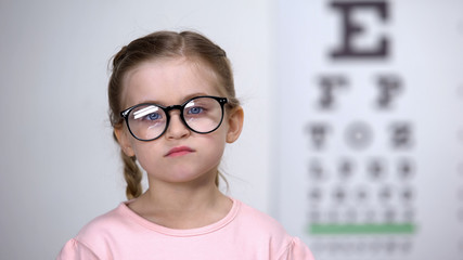 Displeased girl standing in eyeglasses, uncomfortable spectacle frames, bad lens