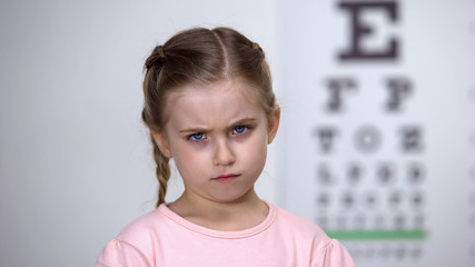 Sad little girl complaining ophthalmologist about vision problems, treatment