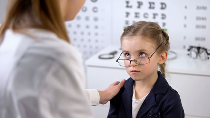 Kind optician supporting schoolgirl with broken eyeglasses, victim of bullying