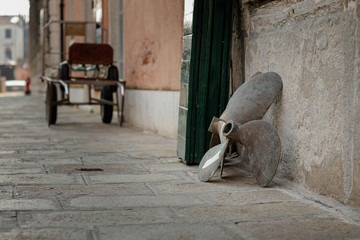 Brass boat propeller leaning against a wall in Venice Italy