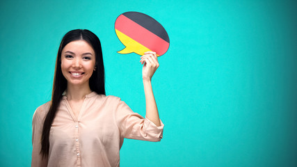 Smiling girl holding German flag speech bubble, learning language, travel ideas