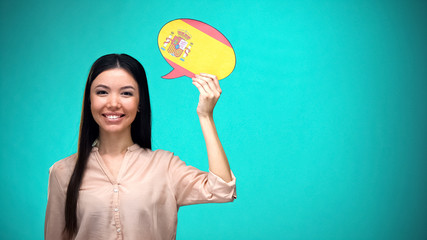 Smiling girl holding Spanish flag speech bubble, learning language, travel ideas