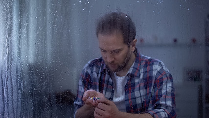 Male war victim holding pills in palm, treating post-traumatic disorder, therapy