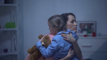 Mother hugging daughter with teddy bear, suffering from bullying, support