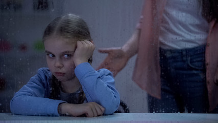 Fototapeta premium Mother scolding little girl behind rainy window, bad behavior in school, problem