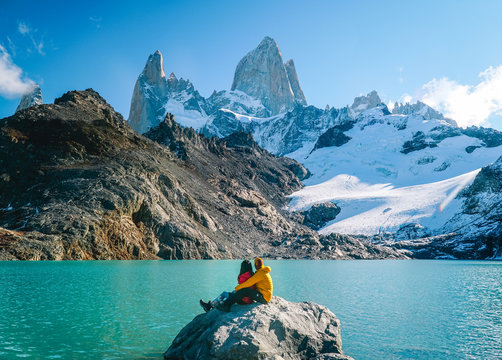 Couple in love at Mount Fitzroy. Scenic view of snowcapped mountain tops of Patagonia trek. Blue sky, turquoise lake and scenic rock landscape. Shot in Argentina. Nature, travel, adventure, hiking.