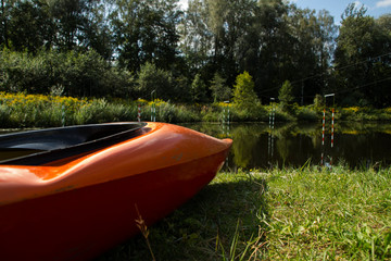 orange slalom boat stands on the bank of the river with a gate for slalom