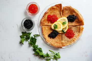 Red and black caviar and pancakes on a white background